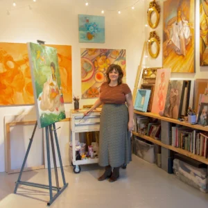 Photo of artist Laura Shull in a studio surrounded by art